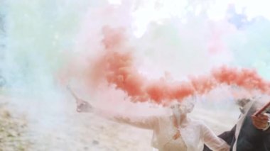 Happy bride and groom waving color red, green, blue smoke in slow motion. High quality FullHD footage
