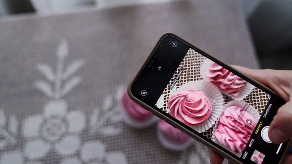 Şef kadın cep telefonuyla fotoğraf çekiyor, şekerler, çilekli gül şekerlemeleri. Yüksek kalite 4k görüntü