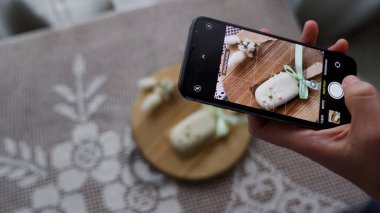 Sosyal medyada fotoğraf paylaşmak için elinde akıllı telefonuyla tatlı cheesecake 'in fotoğraflarını çeken bir kadın. Lezzetli kekten zevk alan çekici genç bir kız. 4k görüntü