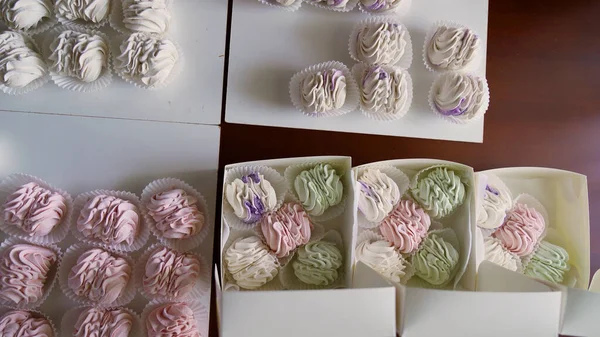A woman is packing delicate light green and pink marshmallows in a gift box. Nearby accessories for packaging. Home business concept. High quality 4k footage