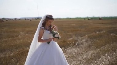 Buğday tarlasında saman balyalarıyla poz veren bohem bir kızın portresi. Ağır çekim. Yüksek kaliteli FullHD görüntüler