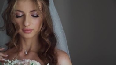 Şık gelin düğün sabahı gelinliğin yanında poz veriyor. Yüksek kaliteli FullHD görüntüler