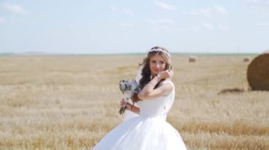Buğday tarlasında saman balyalarıyla poz veren bohem bir kızın portresi. Ağır çekim. Yüksek kaliteli FullHD görüntüler