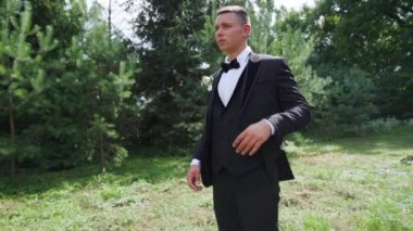 Yakından seksi bir adam park yerinde daha iyi papyon takıyor. Dışarıdaki kameraya bakan seksi erkek portresi. Büyüleyici damat bahçede kendini gergin hissediyor. Yüksek kaliteli FullHD görüntüler