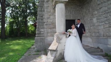 Düğün günlerinde genç bir çift. Damat kalenin yanındaki geline yaklaşıyor. Şefkat anı. Yüksek kaliteli FullHD görüntüler