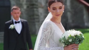 Düğün günlerinde genç bir çift. Damat kalenin yanındaki geline yaklaşıyor. Şefkat anı. Yüksek kaliteli FullHD görüntüler