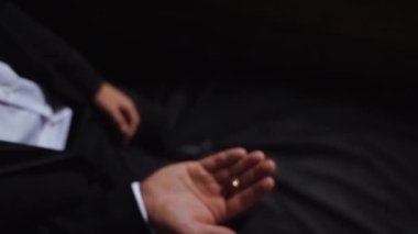 Damat kusar ve nikah yüzüklerini birkaç kez tutar. Düğün sabahı detayları. Ağır çekimde yakın çekim. Yüksek kaliteli FullHD görüntüler