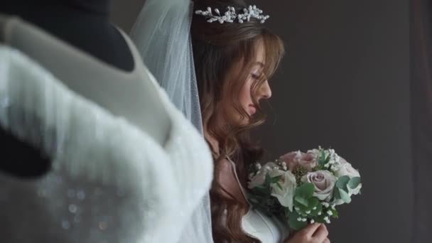 Элегантная Невеста Позирует Возле Висящего Свадебного Платья Утром День Свадьбы — стоковое видео