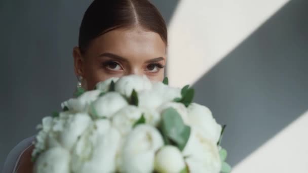 結婚式の日の朝 ぶら下がっているウェディングドレスの近くにポーズをとるエレガントな花嫁 高品質のフルHd映像 — ストック動画