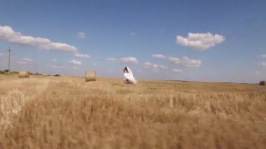 Yazın hasat alanında saman balyalarıyla yürüyen çift. Havadan ateş edildi. Yüksek kalite 4k görüntü