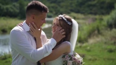 Dağ nehrinin yakınında koşan bir düğün çifti. Damat gelini elinde tutarak döndürüyor. Mutlu bir aile. Steadycam çekimi. Yüksek kaliteli FullHD görüntüler