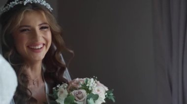 Kameraya bakan çekici esmer kızın yakın plan portresi. Sabahları bir otelde ya da dairede beyaz elbiseli lüks moda gelini. Güzel saç stili ve makyaj. Tam HD görüntüler