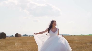 Sahada buğdayla koşan beyaz elbiseli mutlu genç kadın. Muhteşem bir manzara. Yavaş çekimde. Yüksek kaliteli FullHD görüntüler