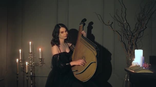 若い美しい女性は 燃焼ろうそくと暗い部屋でウクライナの楽器バンデューラで再生されます 高品質4K映像 — ストック動画