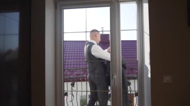 Genç işadamı ceketini evde balkonda giyiyor, ağır çekimde. Yüksek kaliteli FullHD görüntüler