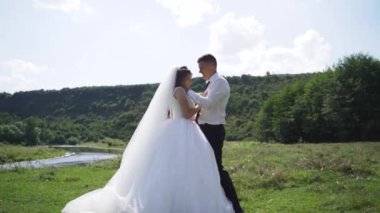 Genç çift aşık gelin ve damat, düğün günü nehir kenarında. Mutluluk ve aşkın tadını çıkar. Steadycam çekimi. Yüksek kaliteli FullHD görüntüler