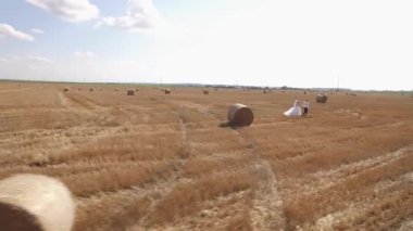 Yazın hasat alanında saman balyalarıyla yürüyen çift. Havadan ateş edildi. Yüksek kalite 4k görüntü