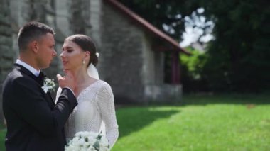 Yeni evlilerin portresi. Güzel Kafkas gelini, damat eski kalenin yanında yürüyor. Sarılmak, sarılmak, öpüşmek. Mutlu evlilik çifti ailesi. Aşık bir erkek. Gelinlik giymiş gelin. Yüksek kalite FullHD