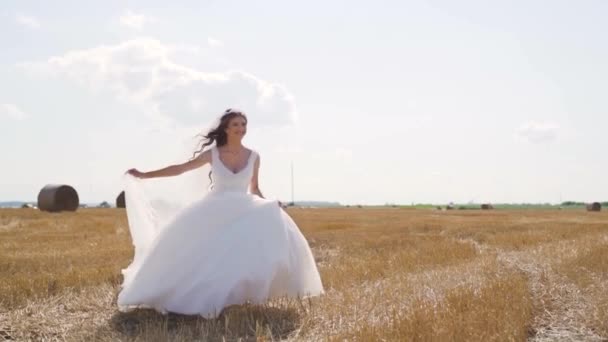 白いドレスを着た幸せな若い女性が小麦で畑を走っています 壮大な風景 スローモーションだ 高品質のフルHd映像 — ストック動画