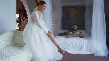 İç etekli seksi bir gelinin pencerenin yanında jartiyer giydiği yakın plan bir fotoğraf. Yüksek kaliteli FullHD görüntüler