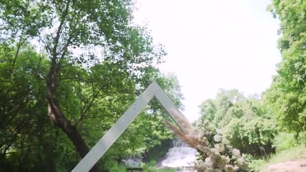 近くの滝の森の屋外の結婚式の会場の美しいボヘミアのアーチの装飾 夏の田舎の結婚式 高品質のフルHd映像 — ストック動画