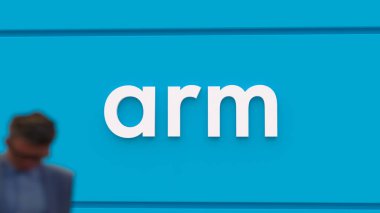 9 Ağustos 2023, kolun logosu mavi duvarda, önünden geçenler bulanık, Arm 'ın beyaz logosu