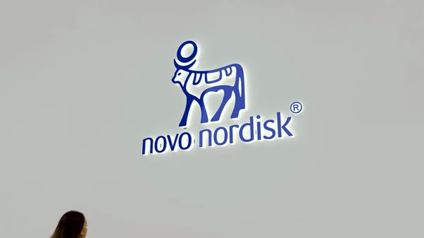 Bir iş bölgesinde Novo Nordisk 'in logosuna odaklan. Önden geçen bulanık biri..
