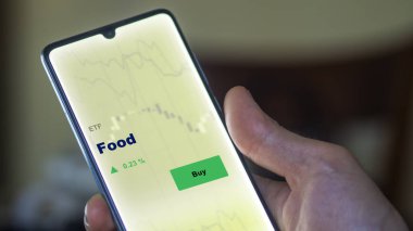 Ekrandaki gıda fonunu analiz eden bir yatırımcı. Bir telefon gıda fiyatlarını gösterir