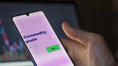 Ekrandaki emtia havuzlarını analiz eden bir yatırımcı. Bir telefon, emtia havuzlarının fiyatlarını gösterir
