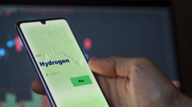 Ekranda hidrojen etf fonunu analiz eden bir yatırımcı. Hidrojen fiyatlarını gösteren bir telefon