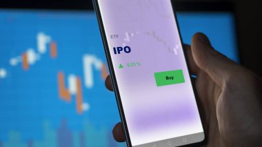 Bir yatırımcı ekrandaki ipo etf fonunu analiz ediyor. Bir telefon halka arz fiyatlarını gösterir