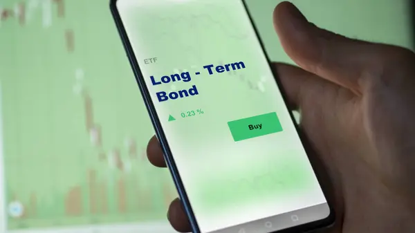 長期的な債券 Etf ファンドをスクリーン上で分析する投資家 電話は長期債の価格を示しています — ストック写真