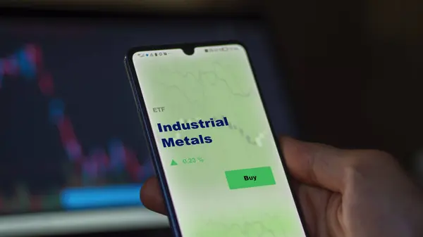 stock image An investor analyzing the industrial metals etf fund on a screen. A phone shows the prices of Industrial Metals