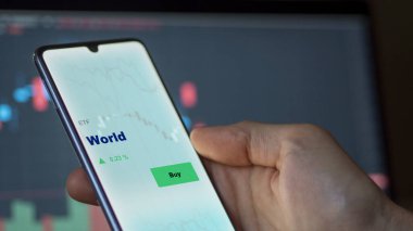 Ekranda dünyayı analiz eden bir yatırımcı. Bir telefon dünya fiyatlarını gösterir