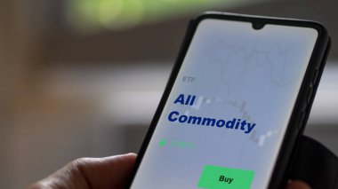 Ekrandaki tüm emtia fonlarını analiz eden bir yatırımcı. Bir telefon tüm malların fiyatlarını gösterir