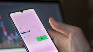 Ekrandaki gümüş etf fonunu analiz eden bir yatırımcı. Silver 'ın fiyatlarını gösteren bir telefon