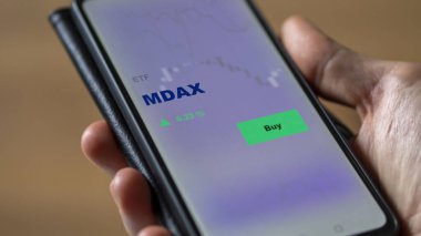 Bir yatırımcı ekrandaki mdax etf fonunu analiz ediyor. Bir telefon MDAX fiyatlarını gösterir