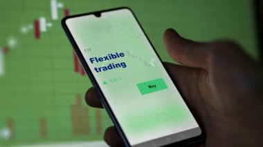 Ekrandaki esnek ticaret fonunu analiz eden bir yatırımcı. Esnek ticaret fiyatlarını gösteren bir telefon