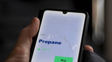 Ekranda propan etf fonunu analiz eden bir yatırımcı. Propan fiyatlarını gösteren bir telefon