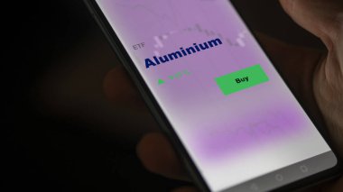 Ekrandaki alüminyum etf fonunu analiz eden bir yatırımcı. Alüminyum fiyatlarını gösteren bir telefon
