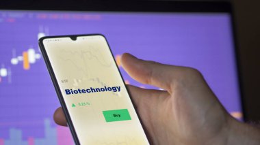 Ekranda biyoteknoloji etf fonunu analiz eden bir yatırımcı. Biyoteknoloji fiyatlarını gösteren bir telefon