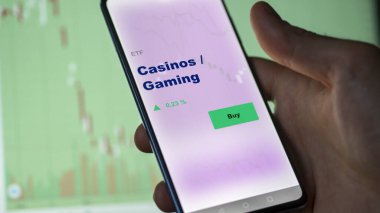 Bir yatırımcı ekranda kumarhaneleri ve oyun fonlarını analiz ediyor. Bir telefon kumarhanelerin / kumarhanelerin fiyatlarını gösterir