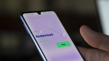 Ekranda internet fonunu analiz eden bir yatırımcı. Bir telefon internetin fiyatlarını gösterir