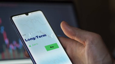 Ekranda uzun vadeli etf fonunu analiz eden bir yatırımcı. Bir telefon uzun vadeli fiyatları gösterir