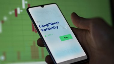 Ekrandaki uzun / kısa dalgalanma etf fonunu analiz eden bir yatırımcı. Bir telefon Uzun / Kısa Volatilite fiyatlarını gösterir