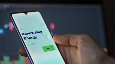 Ekranda yenilenebilir enerji etf fonunu analiz eden bir yatırımcı. Bir telefon yenilenebilir enerji fiyatlarını gösterir