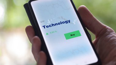 Ekrandaki teknoloji fonunu analiz eden bir yatırımcı. Teknolojinin fiyatlarını gösteren bir telefon