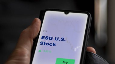 ABD hisse senedi fonunu ekranda analiz eden bir yatırımcı. ESG A.B.D. hisselerinin fiyatlarını gösteren bir telefon.