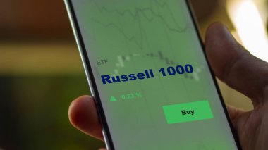 Bir yatırımcı ekranda Russel 1000 etf fonunu analiz ediyor. Bir telefon Russell 1000 'in fiyatlarını gösteriyor.