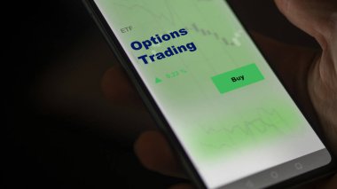 Ekranda etf fonu opsiyonlarını analiz eden bir yatırımcı. Bir telefon seçeneklerin fiyatlarını gösterir